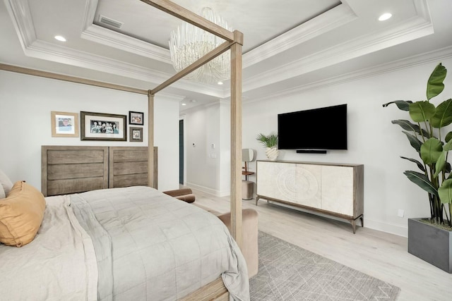 bedroom with a notable chandelier, visible vents, a tray ceiling, and wood finished floors