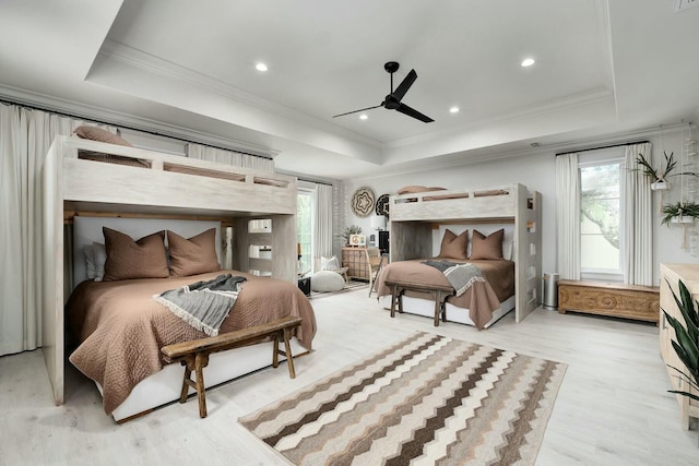 bedroom featuring a raised ceiling, light wood-style flooring, and crown molding