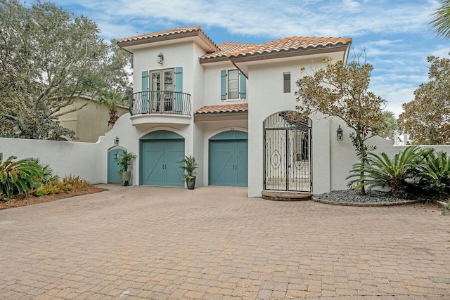 mediterranean / spanish-style home featuring a balcony, fence, stucco siding, a tile roof, and decorative driveway