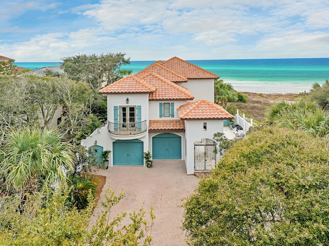 mediterranean / spanish house featuring stucco siding, a tile roof, decorative driveway, an attached garage, and a balcony