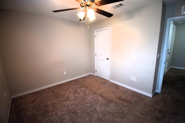 spare room with ceiling fan and dark carpet