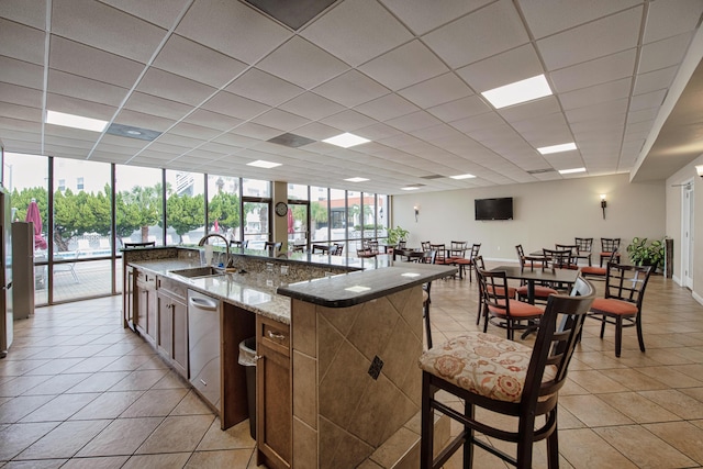 909 Santa Rosa Blvd Unit 611, Fort Walton Beach, FL 32548 - kitchen with light stone counters, light tile patterned flooring, a paneled ceiling, a sink, and a large island with sink