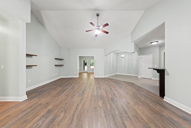 unfurnished living room with ceiling fan, dark hardwood / wood-style floors, and high vaulted ceiling