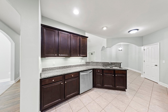 kitchen featuring sink, light stone counters, dark brown cabinetry, stainless steel dishwasher, and kitchen peninsula