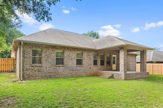 rear view of property featuring a lawn and a patio