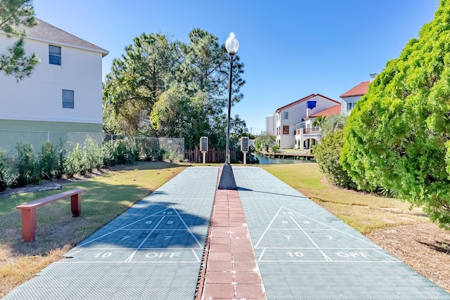 view of home's community featuring shuffleboard, fence, and a yard