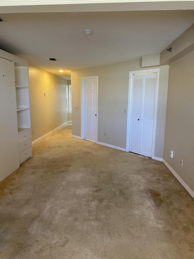 unfurnished bedroom with light carpet, baseboards, visible vents, and multiple closets