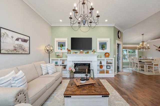 living room featuring hardwood / wood-style flooring, ornamental molding, a fireplace, and a chandelier