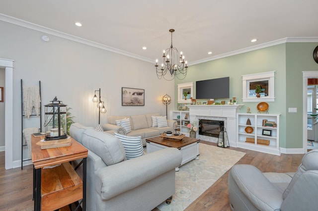 living room with an inviting chandelier, ornamental molding, wood-type flooring, and a fireplace