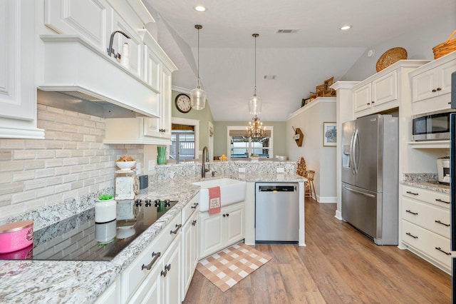 kitchen featuring vaulted ceiling, decorative light fixtures, sink, white cabinets, and stainless steel appliances