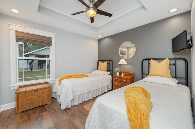 bedroom featuring dark hardwood / wood-style floors, a raised ceiling, and ceiling fan