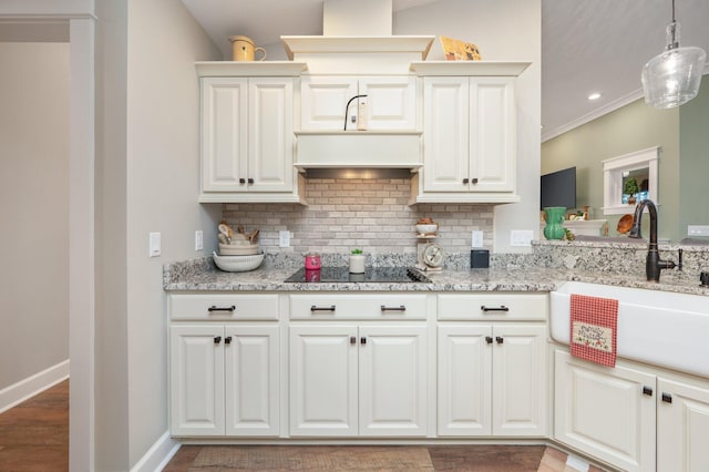 kitchen featuring sink, light stone counters, hanging light fixtures, black electric stovetop, and decorative backsplash