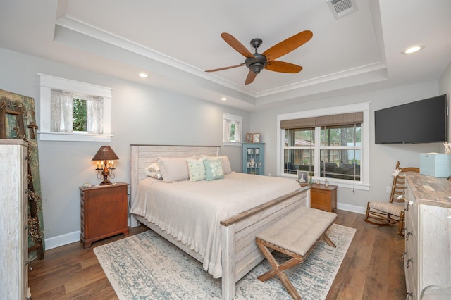 bedroom featuring dark hardwood / wood-style floors, a raised ceiling, and ceiling fan