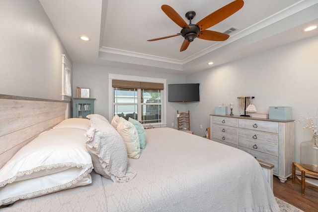 bedroom with ceiling fan, dark hardwood / wood-style floors, and a raised ceiling