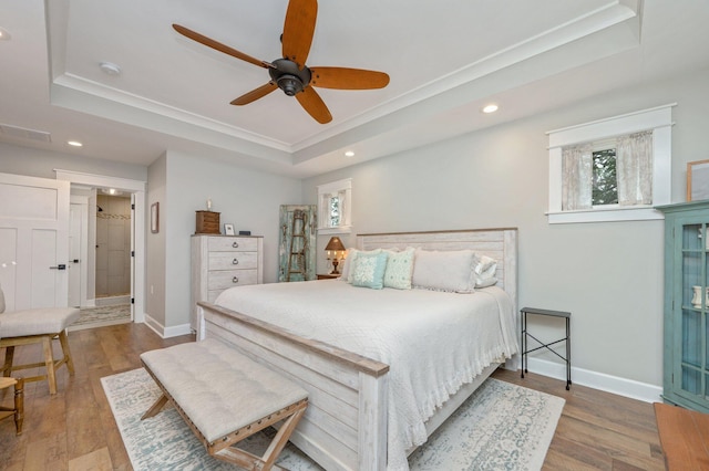 bedroom with hardwood / wood-style floors, a raised ceiling, and ceiling fan