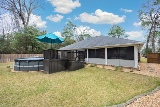 back of house featuring a covered pool, a sunroom, and a lawn