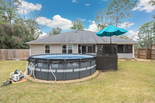 back of property featuring a fenced in pool, a sunroom, and a lawn