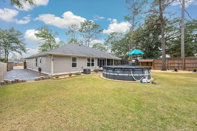 rear view of property with central AC unit, a yard, and a covered pool