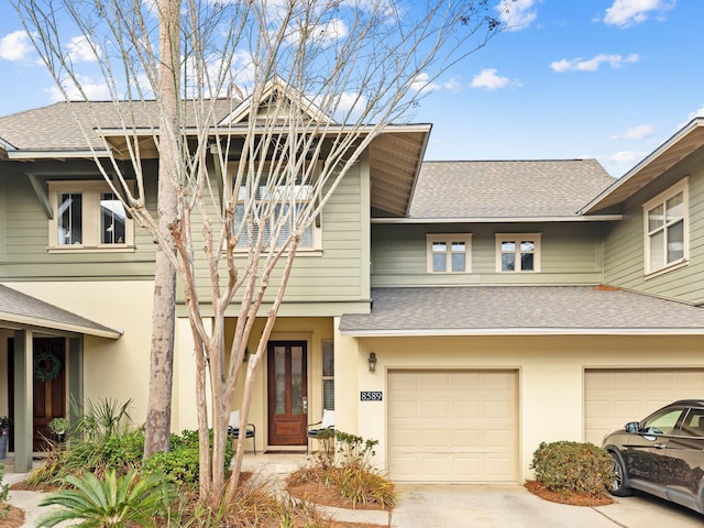 view of front facade featuring a garage, driveway, a shingled roof, and stucco siding