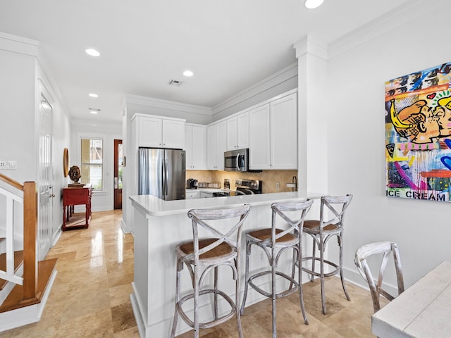 kitchen with a peninsula, white cabinetry, appliances with stainless steel finishes, and light countertops