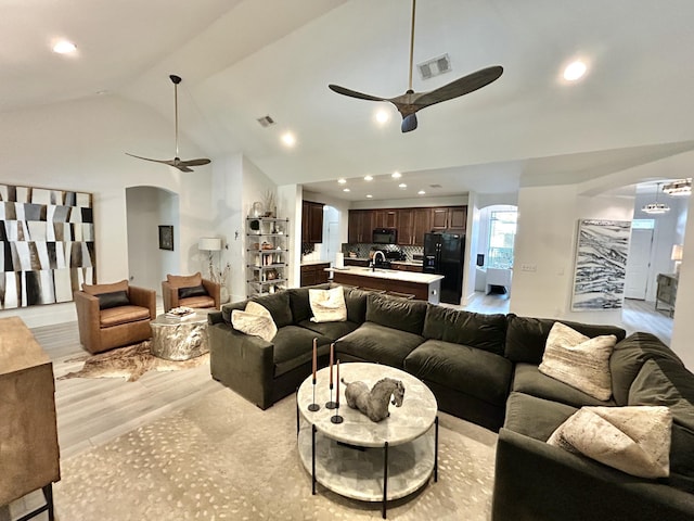 living room with sink, high vaulted ceiling, ceiling fan, and light wood-type flooring