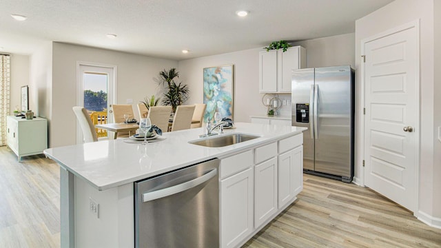 kitchen featuring appliances with stainless steel finishes, a sink, a center island with sink, and white cabinetry