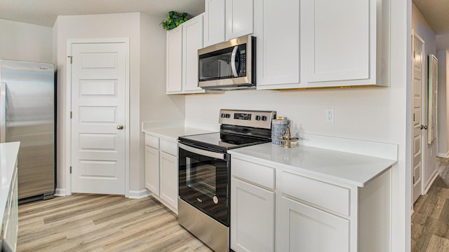 kitchen featuring stainless steel appliances, white cabinetry, baseboards, light wood-style floors, and light countertops