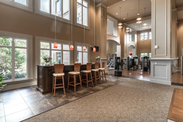 community lobby featuring hanging light fixtures, indoor bar, and a towering ceiling