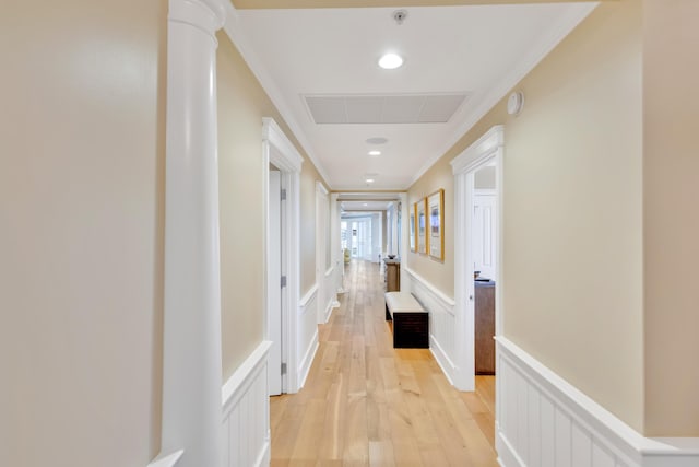 corridor featuring ornamental molding, light wood-type flooring, and decorative columns