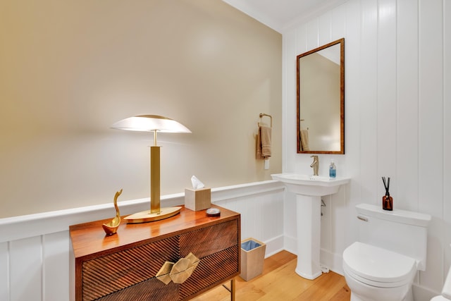 bathroom with crown molding, toilet, and hardwood / wood-style floors