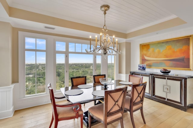 dining room featuring light hardwood / wood-style flooring, crown molding, a chandelier, and a raised ceiling