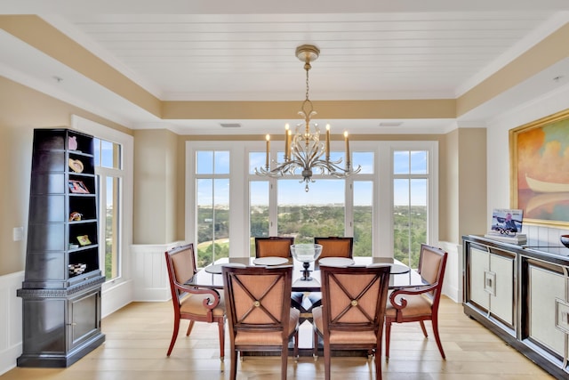 dining space featuring light wood-type flooring, crown molding, a healthy amount of sunlight, and a raised ceiling