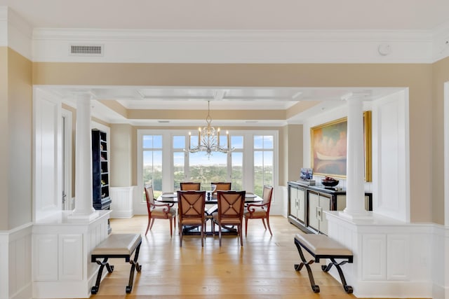 dining room featuring decorative columns, crown molding, and light hardwood / wood-style floors