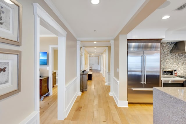 hallway with light hardwood / wood-style flooring, ornate columns, and ornamental molding