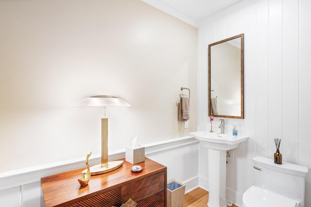 bathroom with toilet, hardwood / wood-style floors, and crown molding