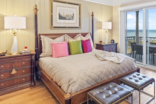 bedroom featuring light hardwood / wood-style floors, a water view, and access to exterior