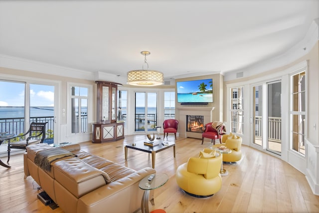 living room with a water view, light hardwood / wood-style floors, and ornamental molding