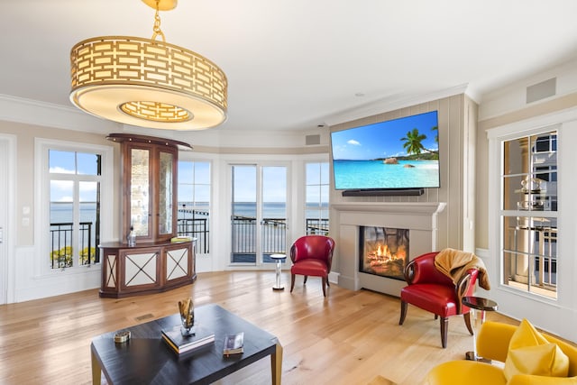 interior space with a water view, light wood-type flooring, and crown molding