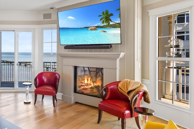 living area with light hardwood / wood-style flooring and ornamental molding