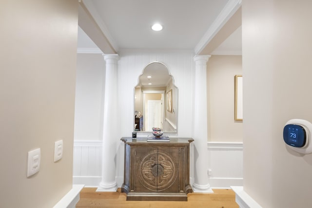 hallway featuring crown molding, ornate columns, and hardwood / wood-style floors