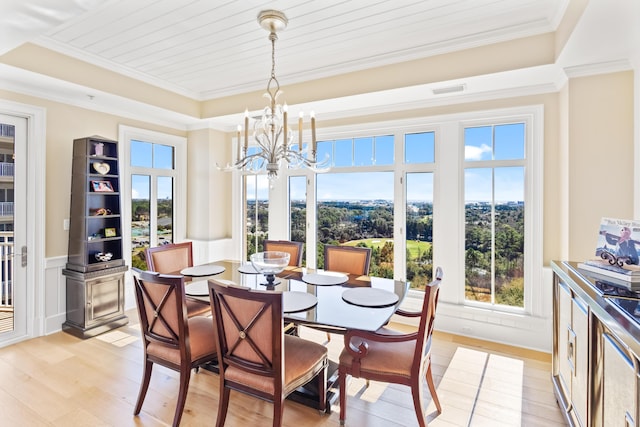 dining room with a tray ceiling, light hardwood / wood-style floors, crown molding, and an inviting chandelier