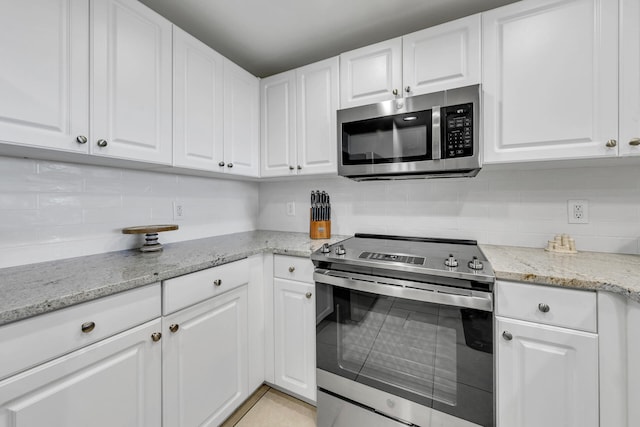 kitchen with appliances with stainless steel finishes, white cabinets, and backsplash