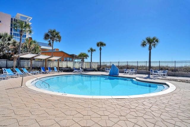 community pool with a patio area and fence