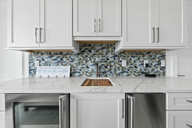 kitchen with white cabinetry, light stone countertops, beverage cooler, and backsplash