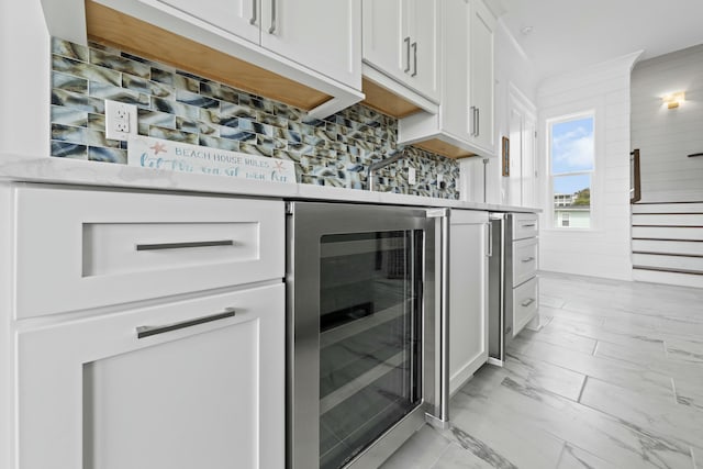 kitchen featuring white cabinets, ornamental molding, tasteful backsplash, and beverage cooler