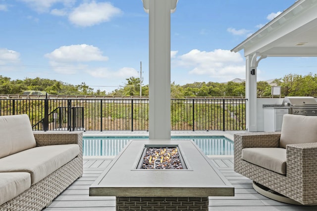 wooden terrace featuring exterior kitchen, a fenced in pool, grilling area, and an outdoor fire pit