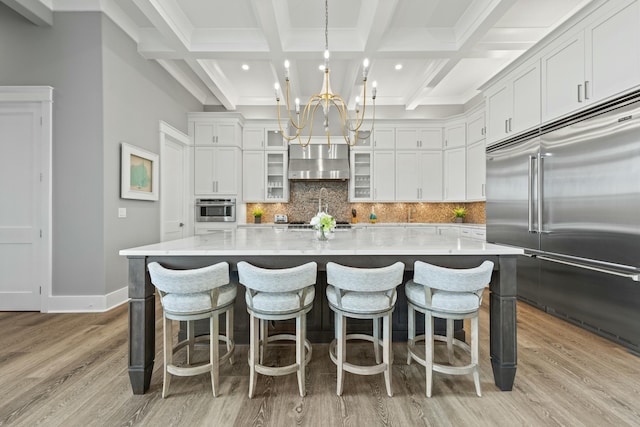 kitchen featuring stainless steel appliances, white cabinetry, a large island with sink, and decorative light fixtures