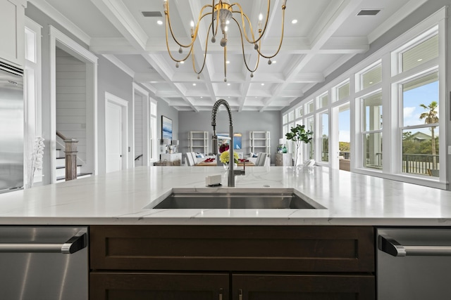 kitchen featuring beamed ceiling, coffered ceiling, sink, and a kitchen island with sink