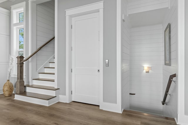 stairs featuring hardwood / wood-style floors and wood walls