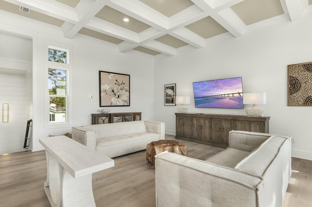 living room with coffered ceiling, light hardwood / wood-style floors, beamed ceiling, and a high ceiling